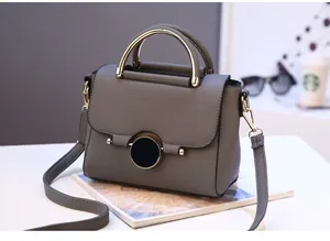 Close-up of grey litchi texture handbag with gold metal handle and round buckle