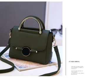 Detail view of dark green leather handbag featuring golden round buckle and metal handle