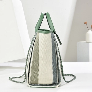 Détail du sac cabas rayé en toile avec bordures en cuir vert et bandoulière en chaîne