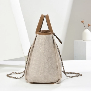 Detail of beige woven texture and brown leather trim on a large chain bucket bag