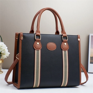 Black pebbled tote bag with brown leather trim and striped strap for daily commute