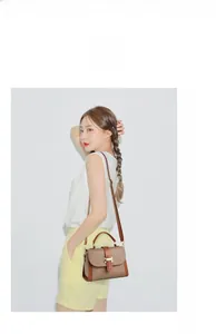 Detail view of khaki and brown patchwork handbag with gold H buckle on model