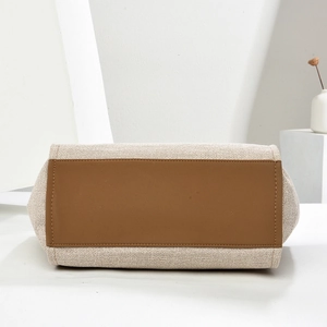 Detail view of the reinforced brown leather base and beige canvas stitching on the tote bag