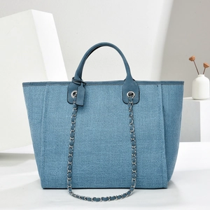 Large blue woven tote bag with leather handles and silver metal chain detail for women