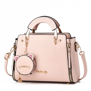 Detail of light pink handbag with gold brand logo and cute glittery cat charm accessory