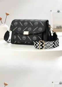 Close-up of black pebbled leather crossbody bag with logo print and woven strap
