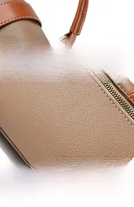 Close-up of litchi texture leather handbag with orange handle and metallic hardware