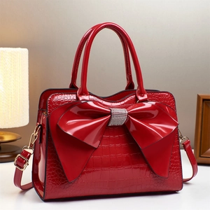 Macro detail of red crocodile pattern handbag with rhinestone bow and gold hardware