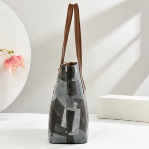 Detailed side view of color-block tote bag with grey and black geometric leather panels