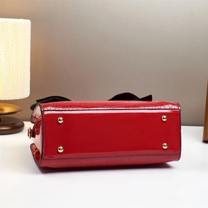 Detail of red patent leather handbag base with gold studs and crocodile texture