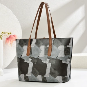 Close-up of color-block tote bag with grey geometric patterns and brown leather handles