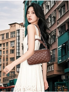 Detail of brown quilted rhombic crossbody bag with woven handle on an urban background