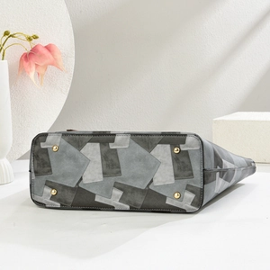 Detailed view of the patchwork tote bag base featuring protective gold metal feet