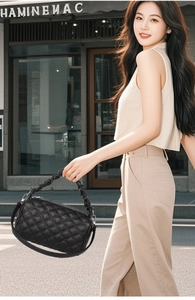 Detail of black quilted leather handbag with ruched handle and silver metal hardware