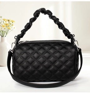 Close-up of black quilted leather handbag with ruched handle and silver zipper detail