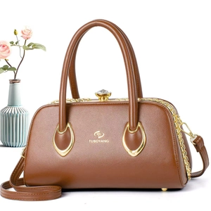 Detail of dark brown lychee leather handbag with golden diamond twist lock and dual handles