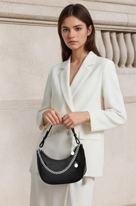 Detail of black pebbled leather hobo bag with silver chain worn with a white suit