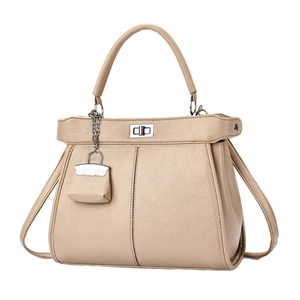 Chique beige handtas van generfd leer met zilveren draaisluiting en kleine hanger