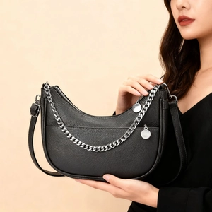 Detail of black pebbled leather half-moon bag with silver metal chain and adjustable strap