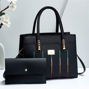 Détail du sac en similicuir noir avec broderie colorée et plaque métallique dorée