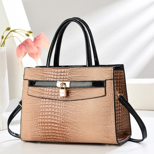 Detailansicht der braunen Kroko-Textur und goldenen Beschläge der Pendler-Handtasche