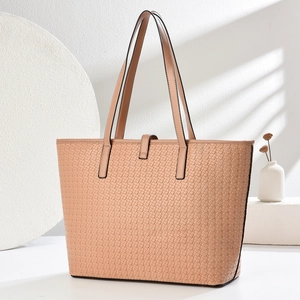 Detail of pink woven tote bag with leather buckle closure and top handles on a white surface