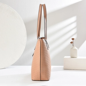 Close-up of woven texture detail and leather handle on a beige vintage tote bag