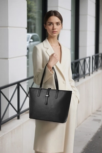 Detail of woven texture on a black tote bag with silver buckle and matte leather finish