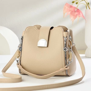 Close-up of beige bucket bag with lychee grain texture and silver metal buckle