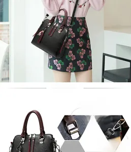 Detail showing the reinforced burgundy handles and decorative tassel on a black handbag