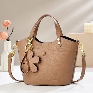 Detail view of brown lychee leather bucket bag with gold hardware and flower charm accessory