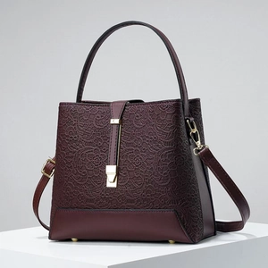 Detail of burgundy bucket bag featuring intricate lace stitching and golden hardware