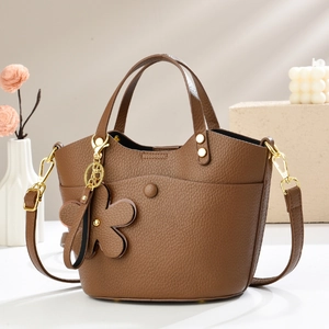 Detail of brown litchi pattern bucket bag with golden hardware and flower pendant