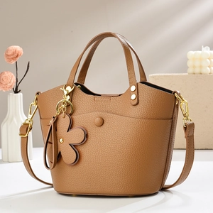 Elegant caramel brown bucket bag in textured faux leather with flower charm for summer