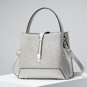 Close-up of light gray leather bucket bag featuring floral lace and gold clasp detail
