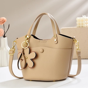 Detailed macro shot of lychee grain leather texture and golden hardware on bucket bag