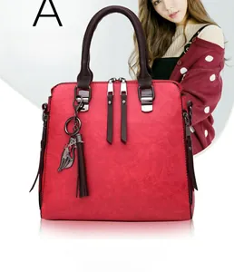 Close-up of red lychee texture leather handbag with dual zippers and cat pendant accessory