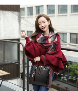 Detail of black pebbled leather handbag with red tassel on model with autumn outfit