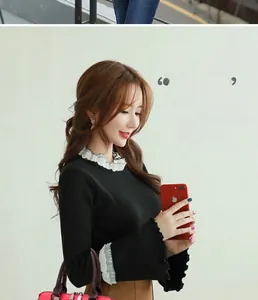 Detailed shot of black knit long-sleeve top featuring elegant white ruffled collar and cuffs