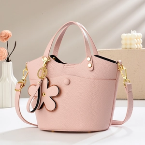 Detail of pink lychee leather bucket bag with floral charm and gold-tone hardware