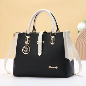 Minimalist bicolor leather tote bag in black and cream with golden heart pendant accessory