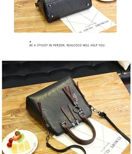 Detail of black faux leather handbag with long tassels and silver cat charm