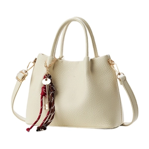 Elegant beige pebbled leather handbag with gold key charm and adjustable crossbody strap