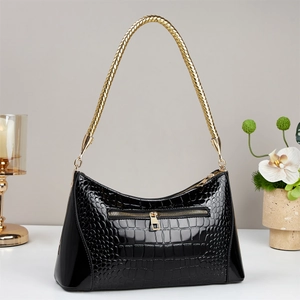 Détail du sac à main noir à motif crocodile avec une poignée tressée dorée élégante