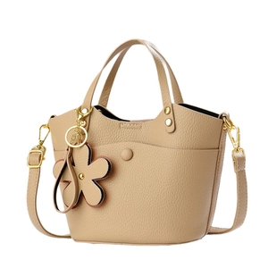 Elegant beige bucket handbag with floral charm and adjustable strap on white background
