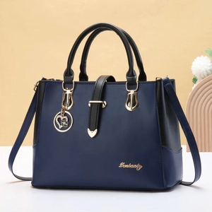 Close-up of large blue handbag featuring gold hardware and a floral heart charm detail