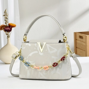 Elegante witte leren handtas met gouden V-logo, decoratieve ketting en schouderband