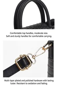 Detail of round handles and polished gold hardware on black crocodile pattern bag