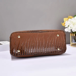 Vue détaillée du fond du sac en cuir crocodile marron avec des pieds en métal doré