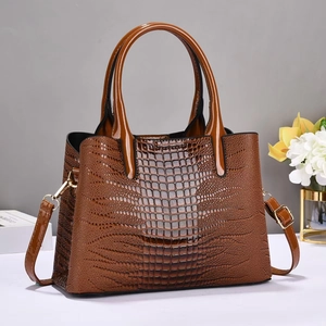 Détail d'un sac à main marron à motif crocodile brillant avec ferrures dorées de luxe